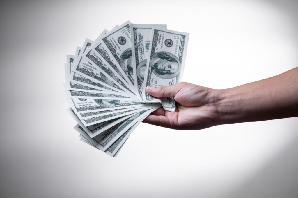 Image of a hand holding 100 dollar bills in a post about the best reasons to save money.